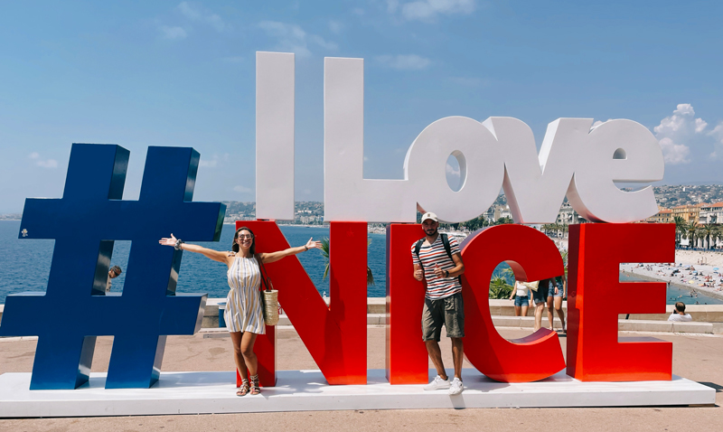 due ragazzi in piedi davanti alla scultura di I Love Nizza, lungo mare