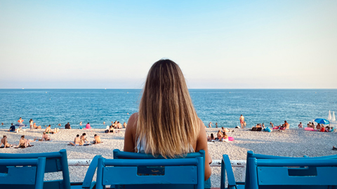 ragazza seduta di spalle che guarda il lungo mare di Nizza